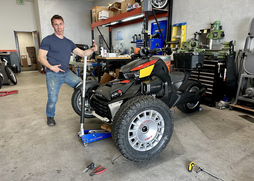 A Can-Am Ryker Rally with the front end lifted on jacks getting a tire change.