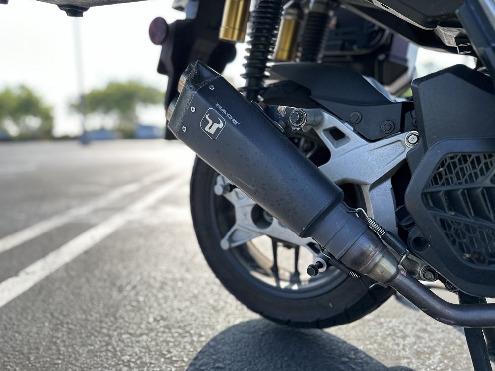 Detail image of an aftermarket exhaust on a Honda ADV150 scooter.
