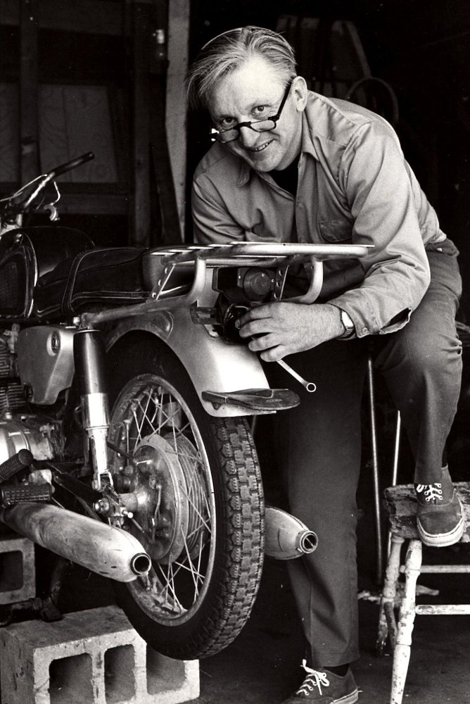 black and white photo of Pirsig wrenching on the rear rack on the Honda