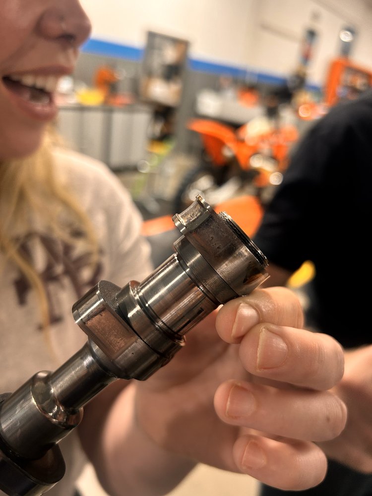 Liz looking at the worn camshaft removed from her motorcycle