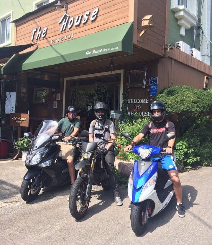 three riders on small motorcycles outside a hostel