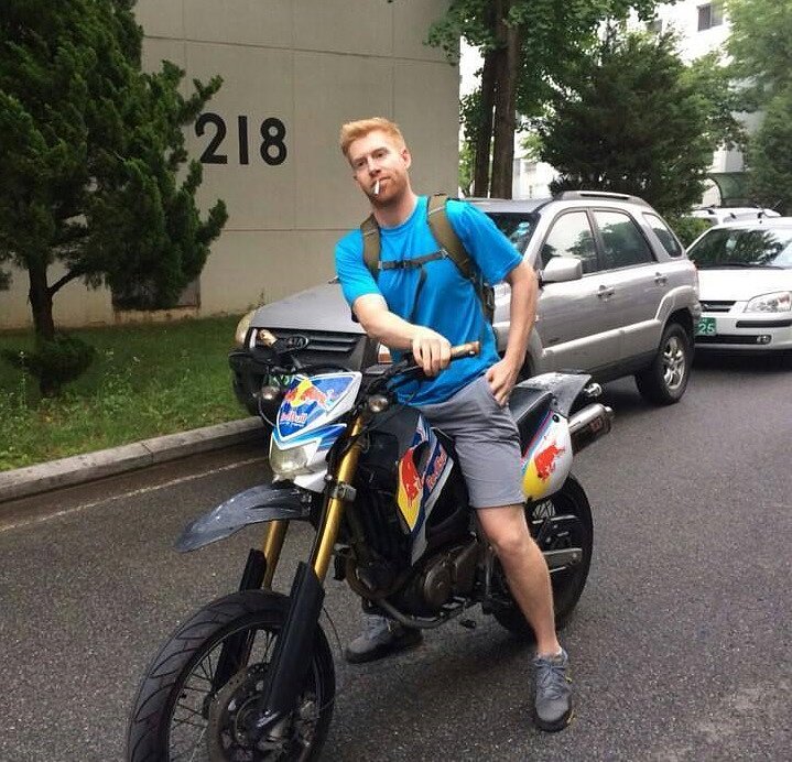 author in shorts and a shirt and no helmet sitting on his RX125 motorcycle