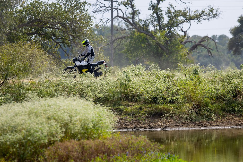 Origin seen in the distance riding by a pond