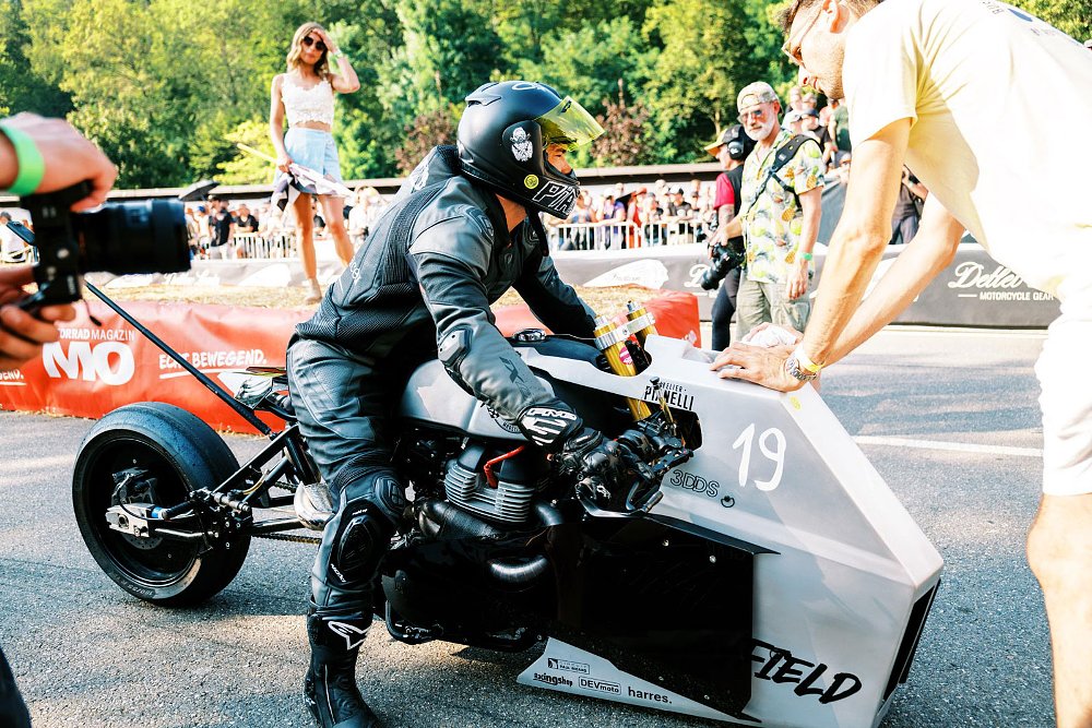 rider sitting at the drag strip on the Royal Enfield custom with a wedge-shaped nose and bare rear section