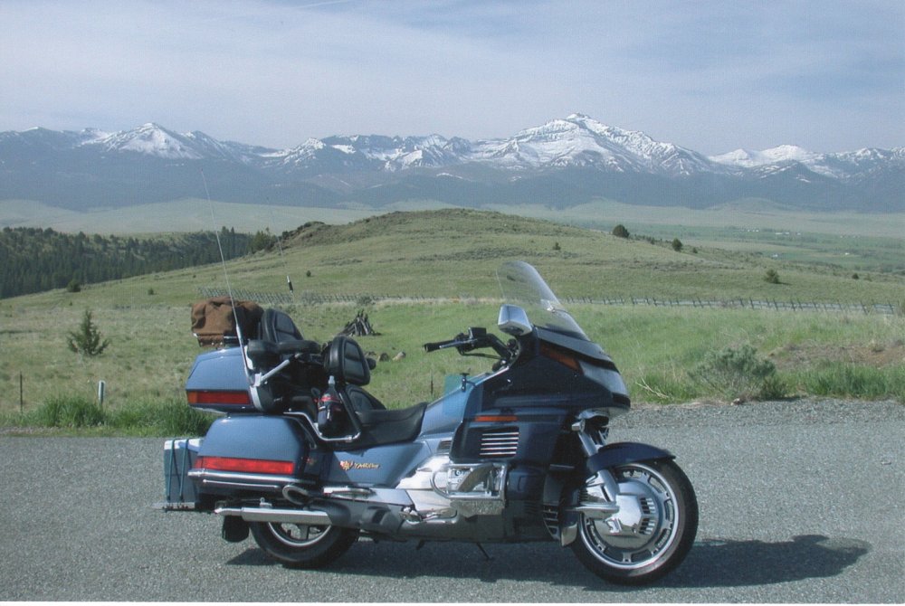 Weaver's blue Gold Wing parked with snow-capped mountains in the distant background