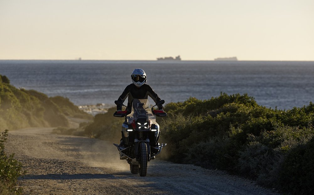 rider standing up on the GS Adventure on a dirt road with the ocean in the background