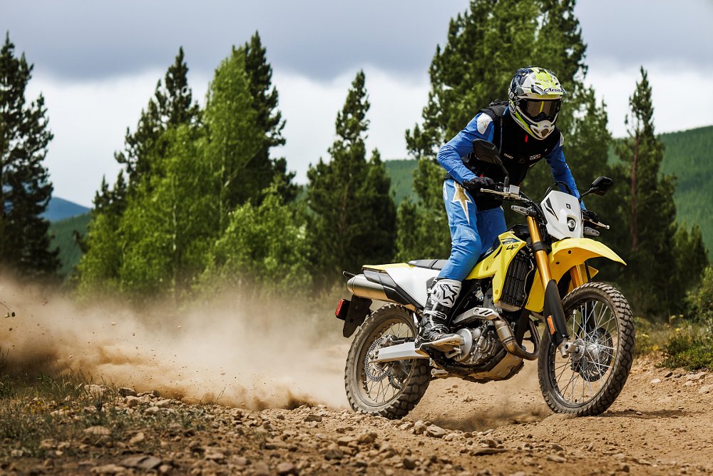 yellow DR-Z4S being ridden on a trail, roosting dirt off the rear tire