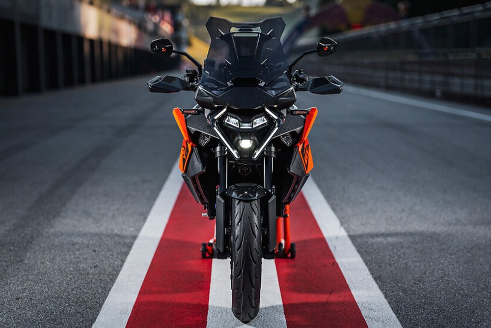 A head-on image of the 2025 KTM 1390 Super Duke GT in the pit lane of a race track.