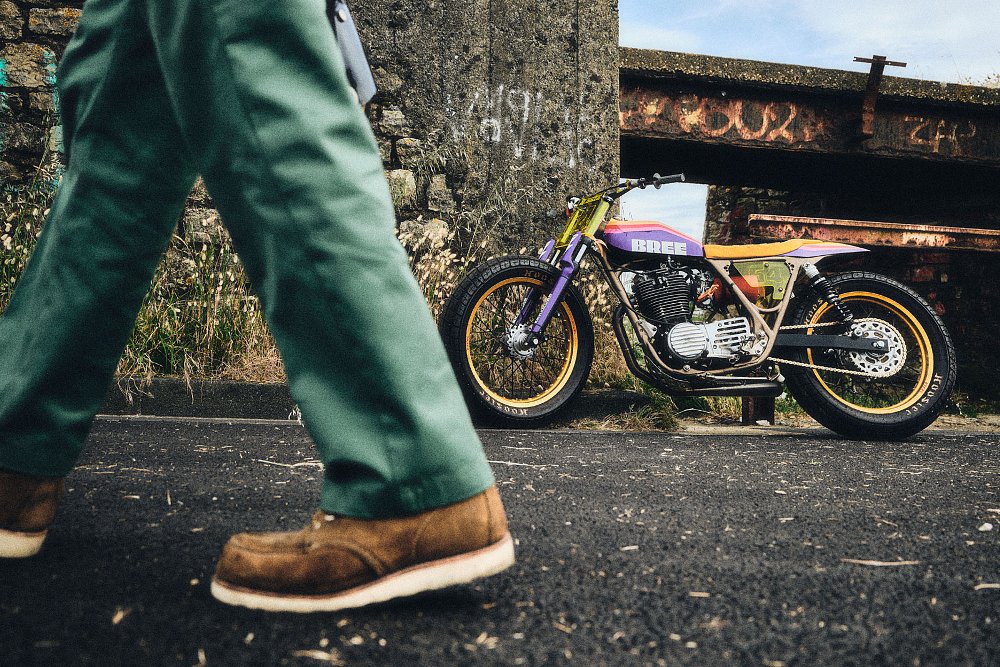 person in Red Wing boots walking by with the motorcycle in the background