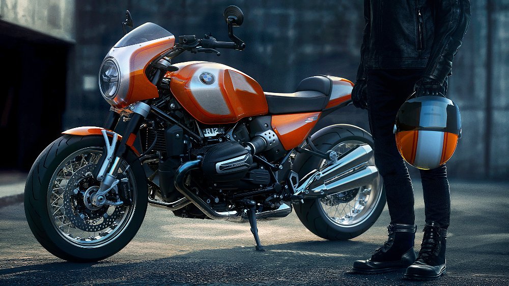 A fashionable rider stands next to an R 12 S. 