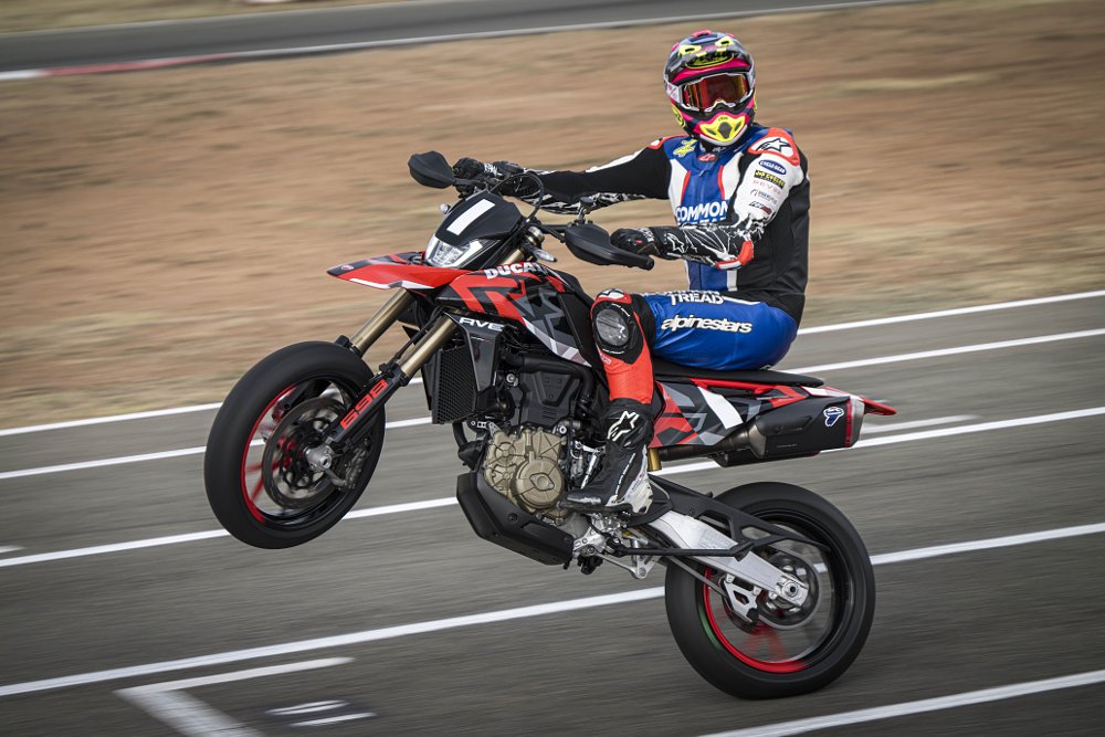 2024 Ducati Hypermotard 698 Mono doing a wheelie on a racetrack.