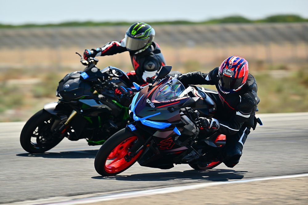 Dustin on the Aprilia RS 457 on the track passing a rider on a larger motorcycle