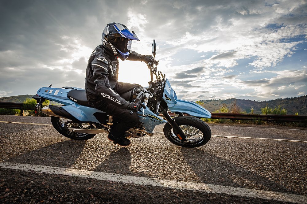 rider on a Suzuki DR-ZSM in a curve in a road with sun in the background