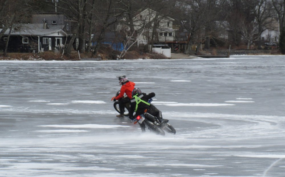 Paul on his orange KTM and Ken on his blue Yamaha close behind as they race in a circle on the lake