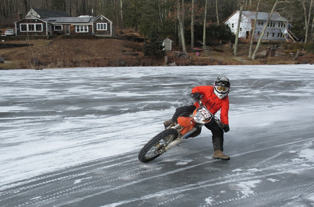 Paul on his orange KTM leaned over on the ice-covered lake
