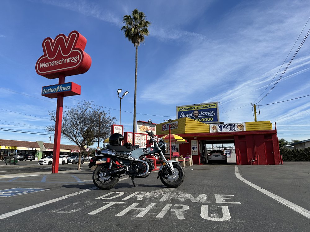 2025 Honda Dax 125 parked in front of a Wienerschnitzel restaurant drive thru.