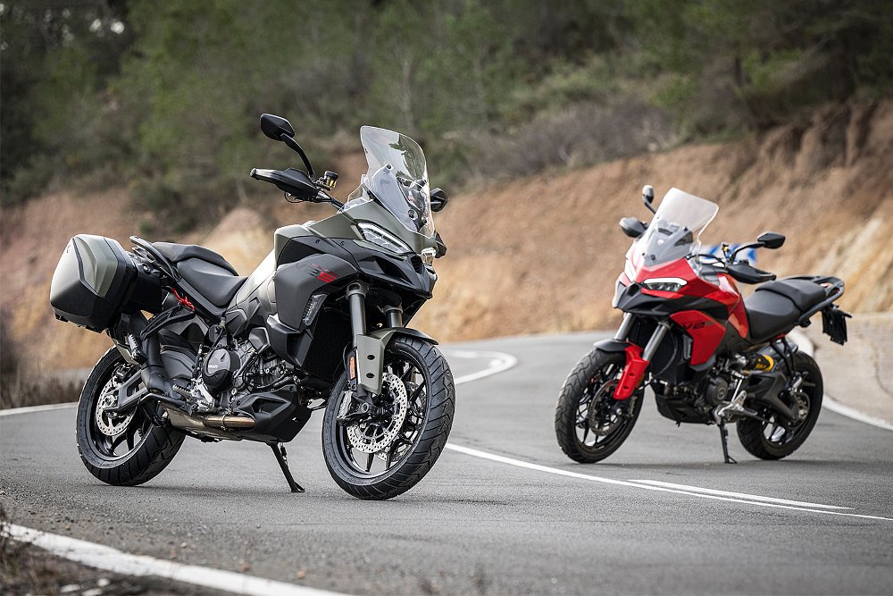 Two Ducati Multistrada V2 S units, in Ducati Red and Storm Green, parked on a twisty road.