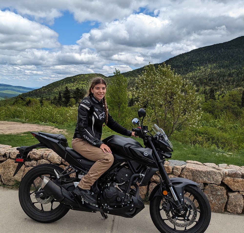 Kate on her black Yamaha MT-03 parked at an overlook on the mountain road