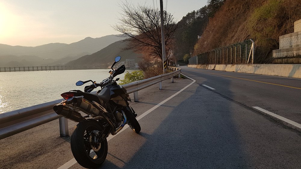 motorcycle parked along a coast road at sunset