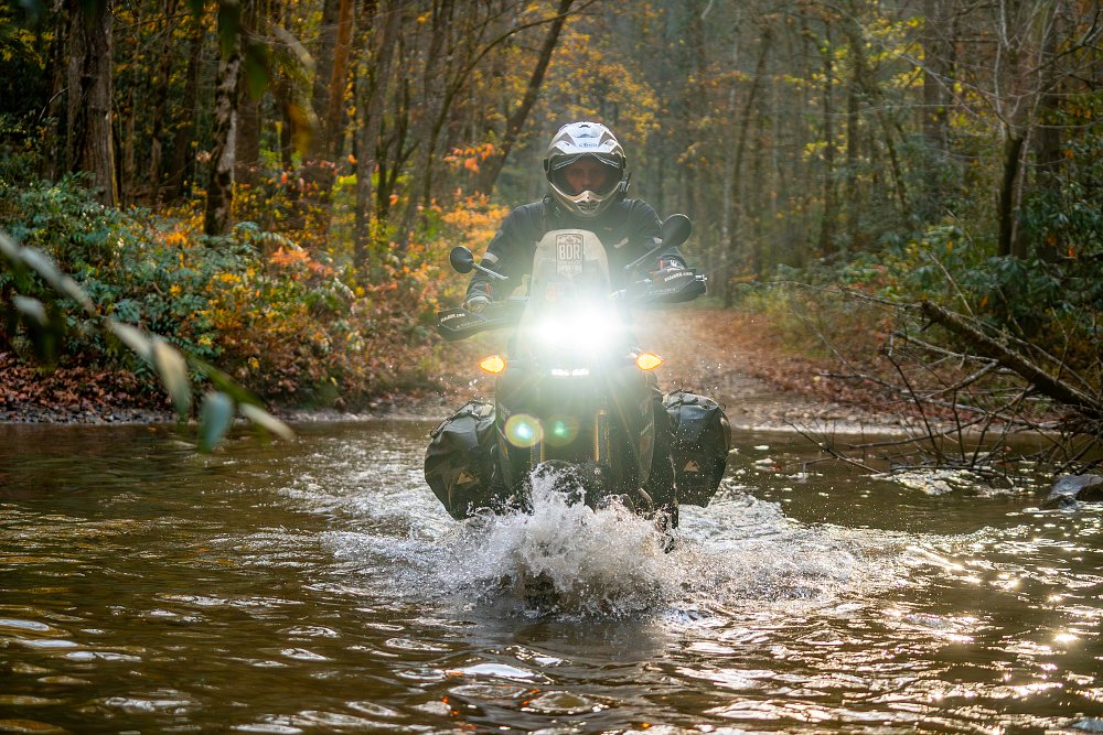 Tim James rides his Yamaha Tenere 700 through waist-deep water. 