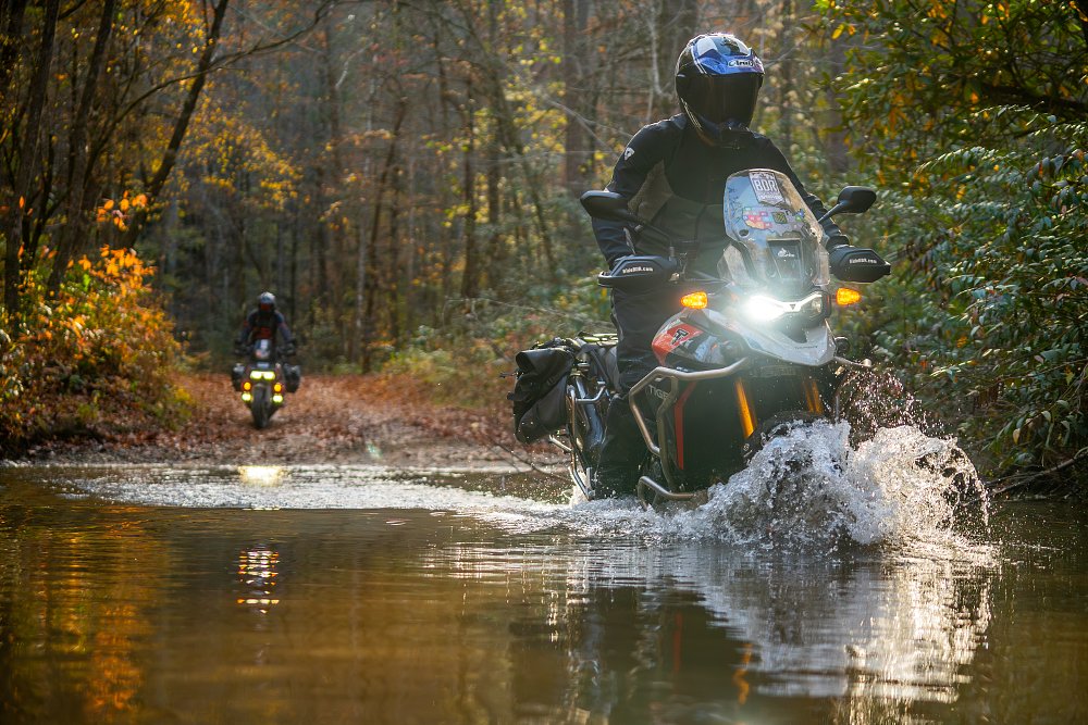 Dustin crosses a river aboard a Triumph Tiger 900 Rally Pro.
