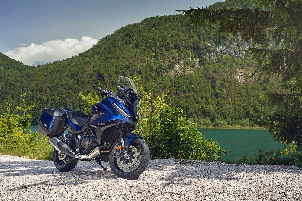 The Honda NT1100 pictured along a lake and mountside.