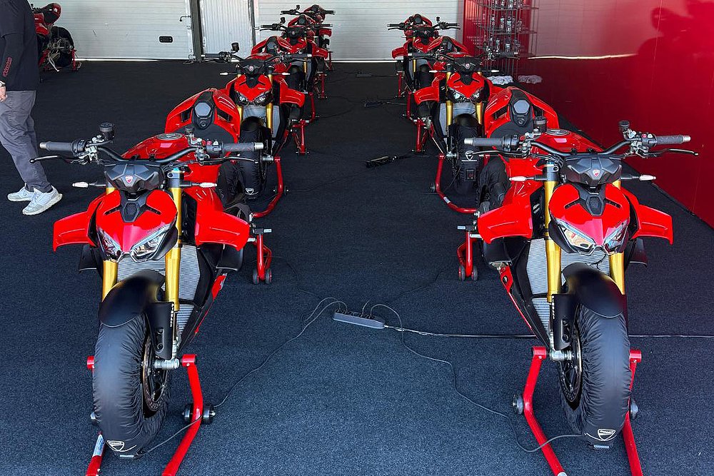 Seven Streetfighter V4 S bikes on front and rear stands with tire warmers.