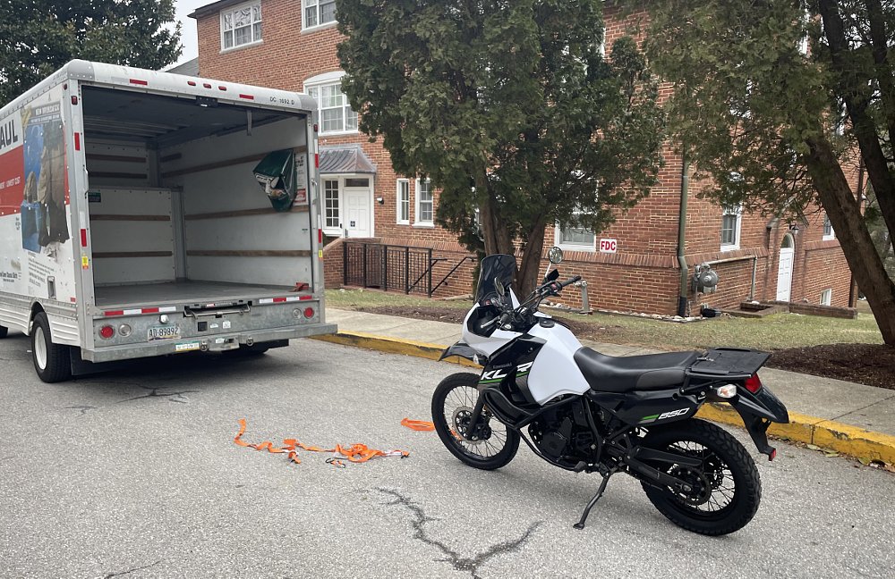 the white KLR650 sitting behind the box truck after being unloaded