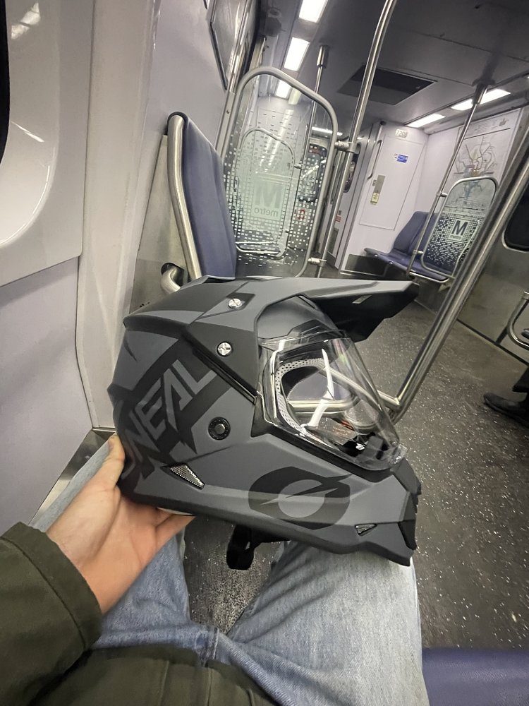 the author holding his dual-sport motorcycle helmet sitting in an empty train car