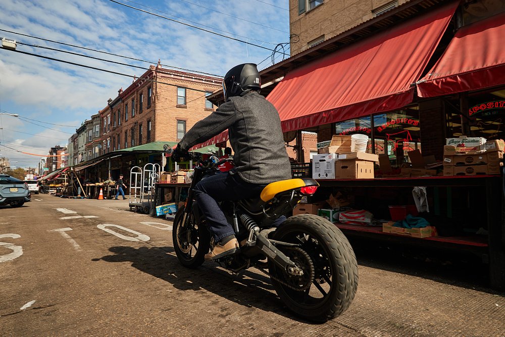 rider on a narrow city street with cars and pedestrians around