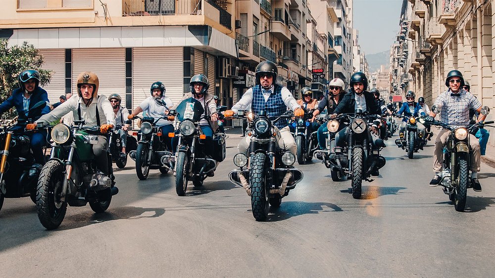 Suited and booted motorcyclists participate in The Distinguished Gentleman's Ride, trundling down an urban street. 