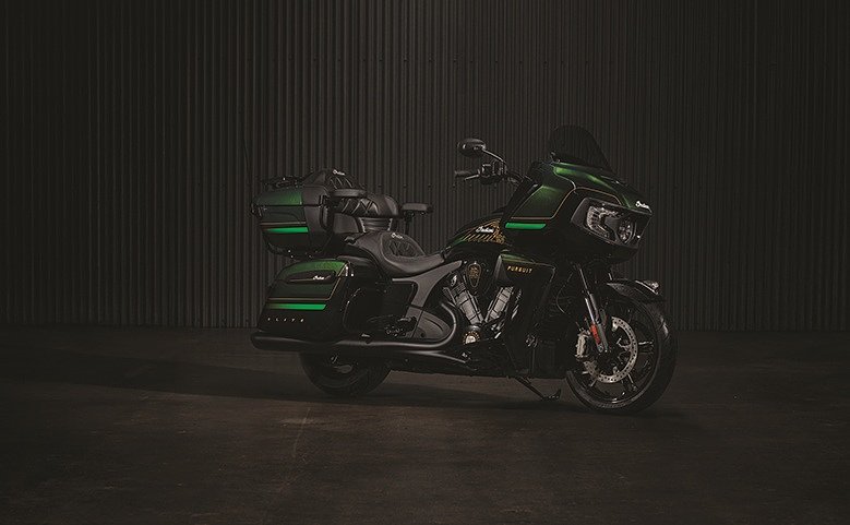 studio image of 2025 Indian Pursuit Elite touring motorcycle in black, green and gold colors