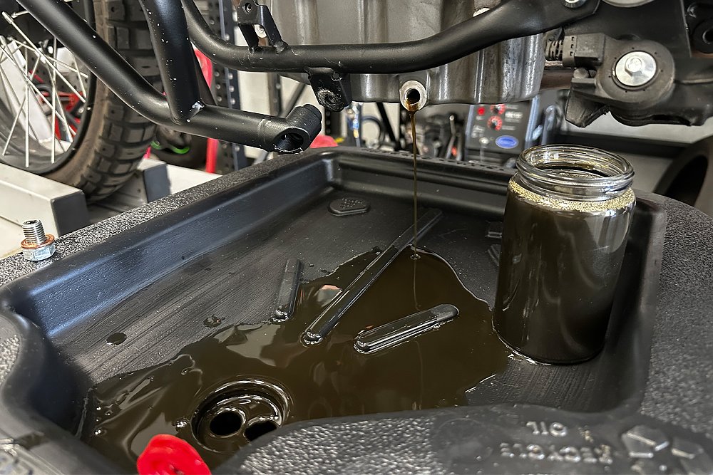 A close-up of oil draining from the CFMOTO Ibex 450's crankcase.
