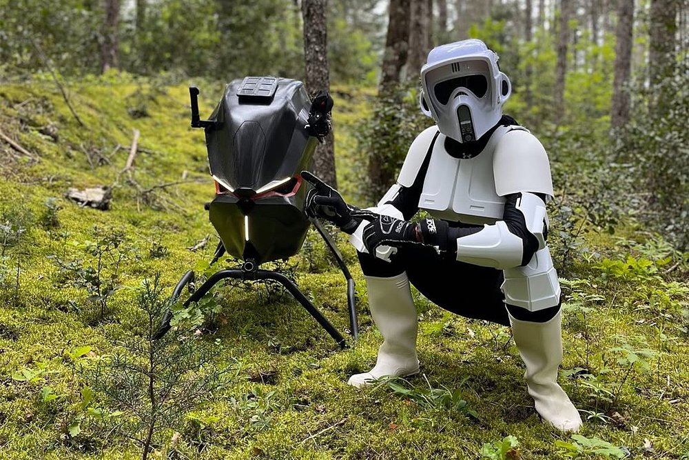 A Volonaut Airbike rider posing next to the bike in an Imperial Scout Trooper costume from Star Wars.