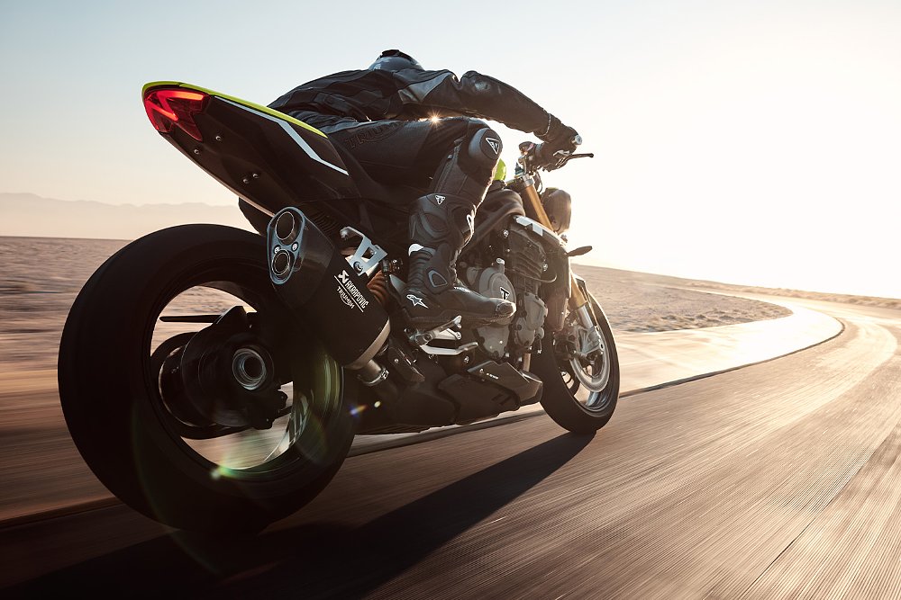 The Speed Triple 1200 RX ridden on track with its Akrapovic exhaust prominently featured.