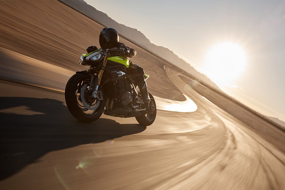 A Speed Triple 1200 RX rider blasting through an S-curve on track.