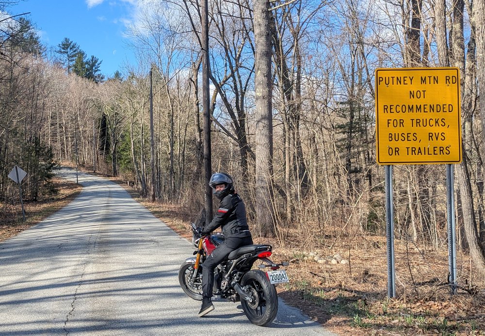 Abby on her Triumph 400 in front of the Putney Mountain Road warning sign