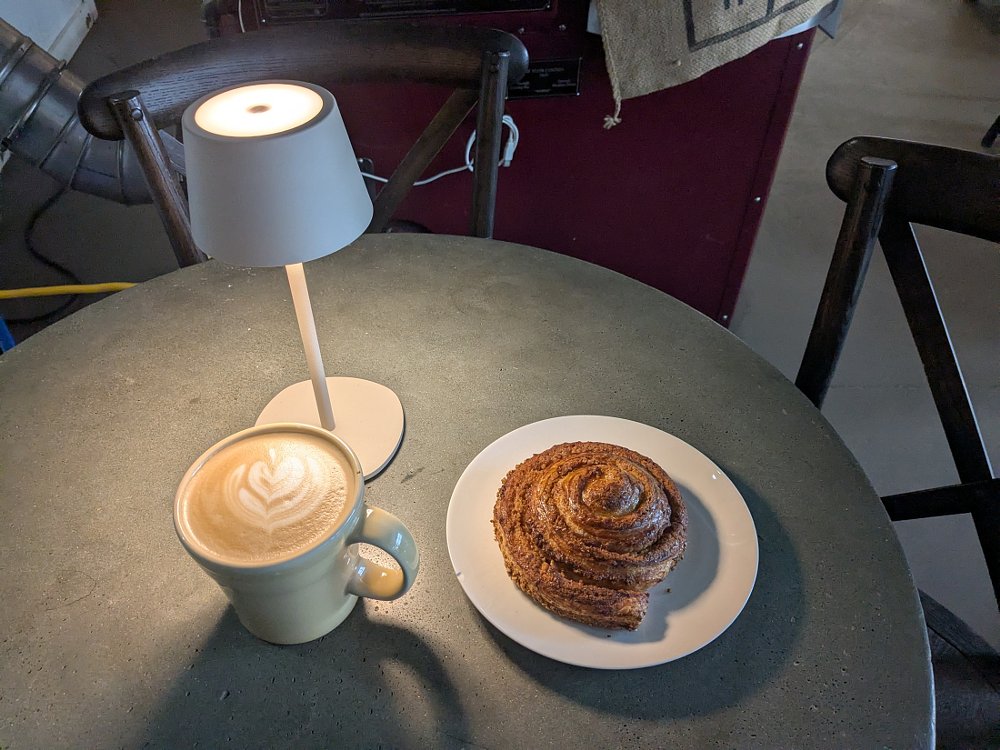 coffee and a cinnamon roll on a cafe table