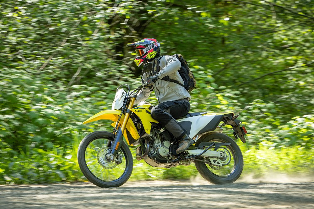2025 Suzuki DR-Z4S riding along a dirt road in the woods.