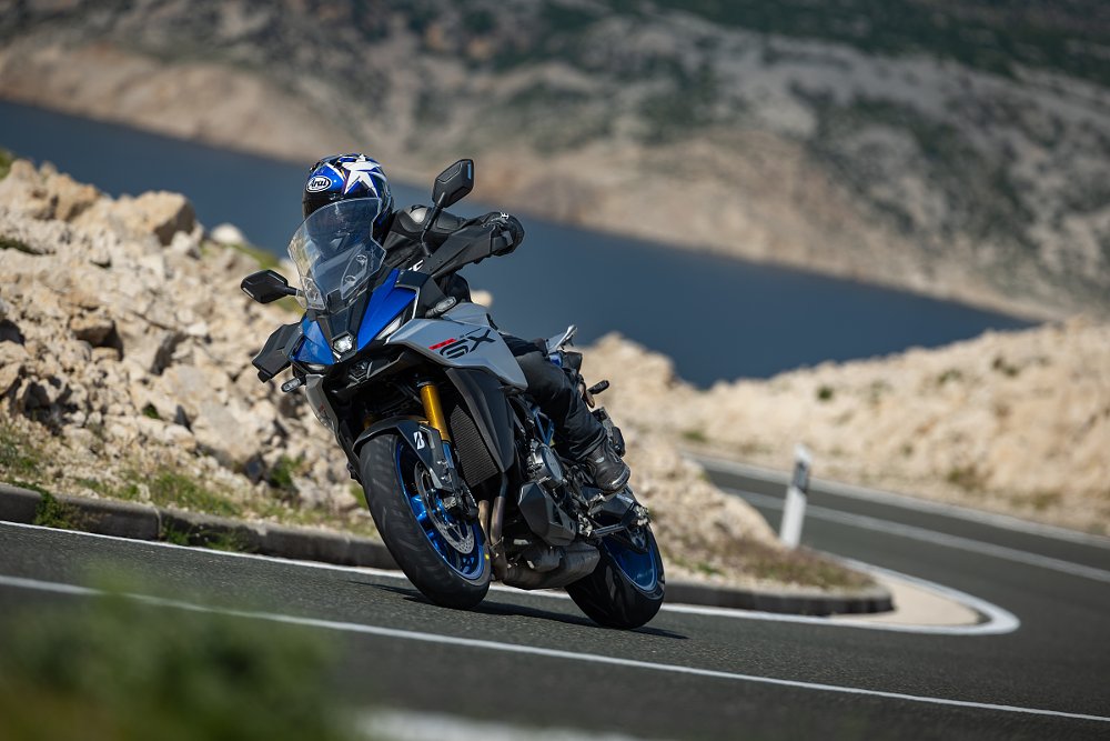 riding the Suzuki GSX-S1000GX through a curve in rocky mountainous terrain