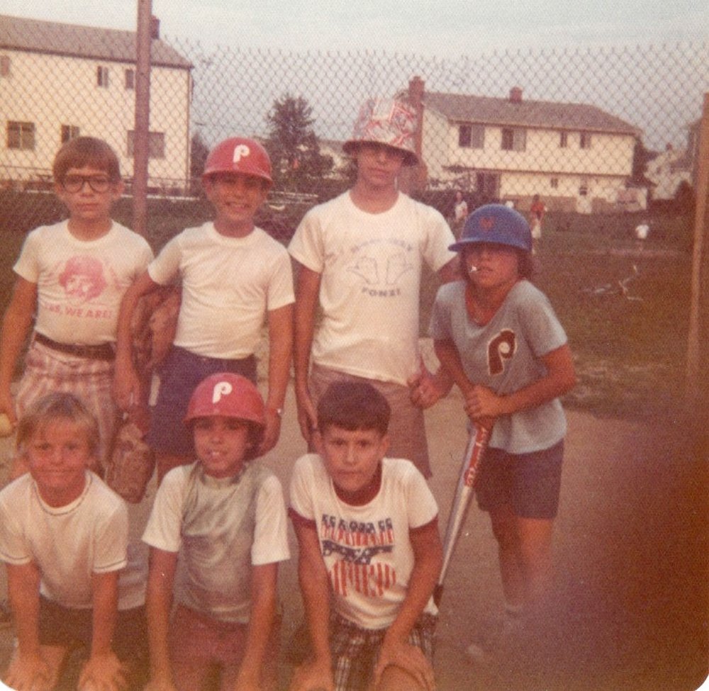group of boys posing at a baseball field with a bicycle on the ground in the background