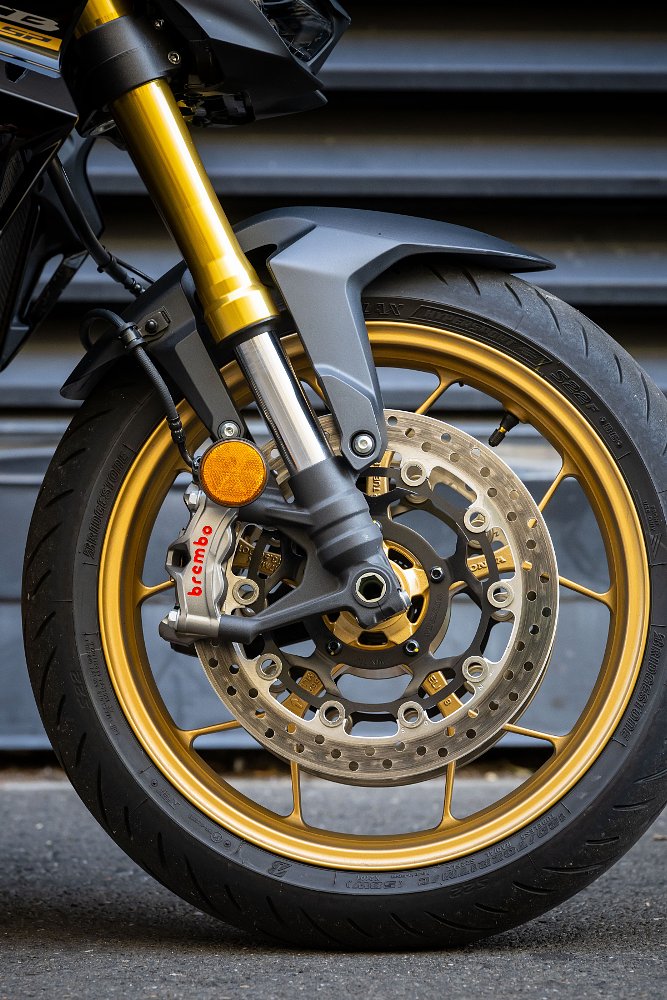 close view of the gold-colored front wheel, gold-toned fork legs, and front brakes