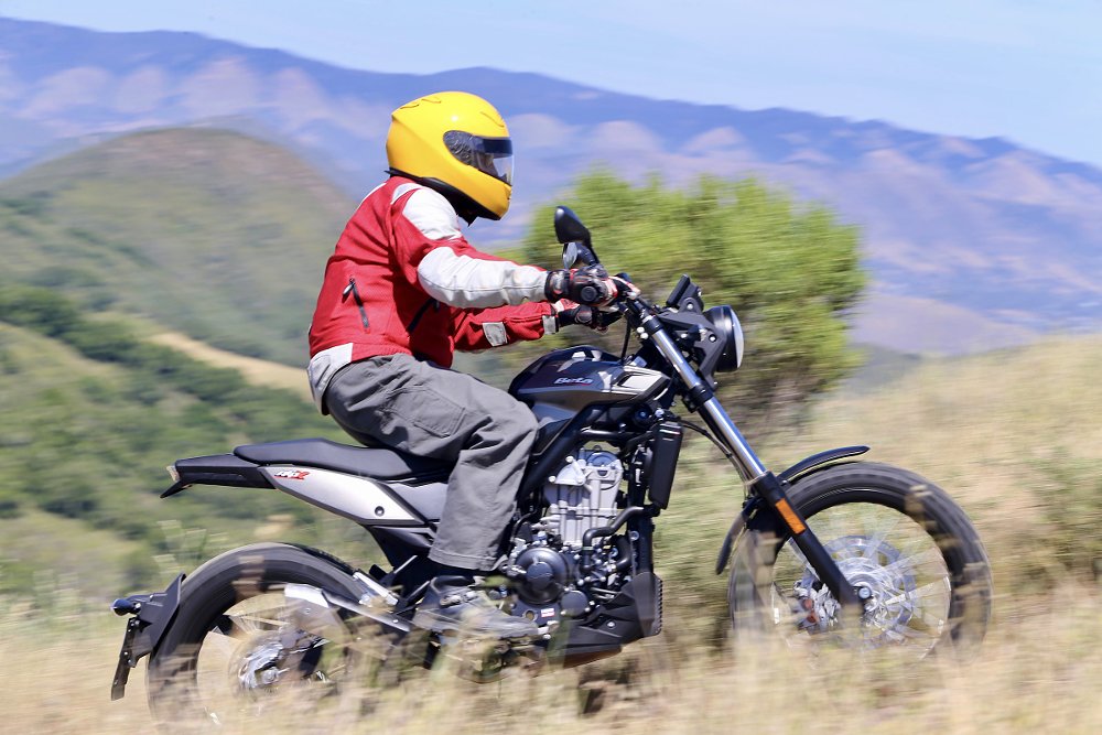 riding the Beta Alp X on a trail through a mountain field