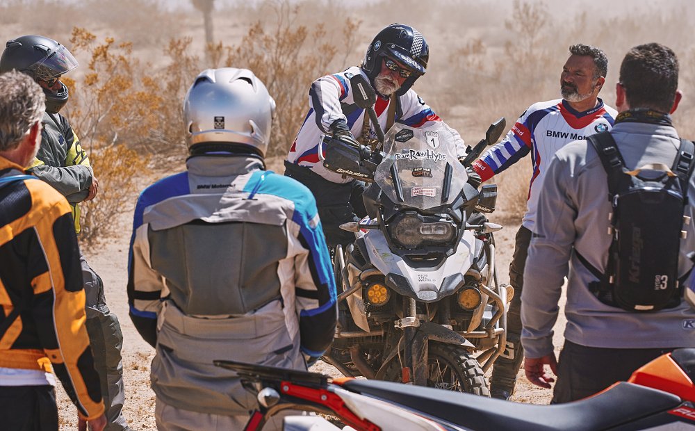 an instructor demonstrates technique on a motorcycle as a group watches