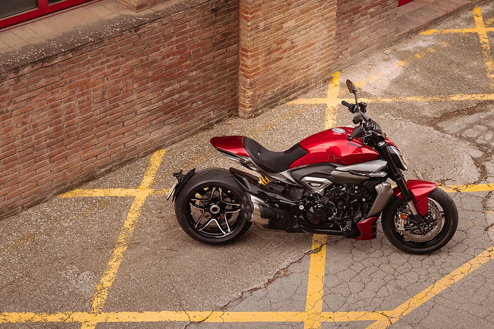 The Ducati XDiavel V4 parked along a brick building.