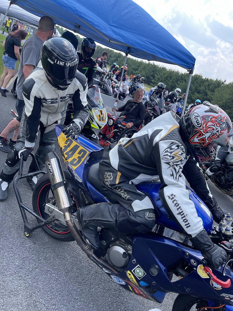 Berlandi on his SV650 in leathers about to go onto the track as a helper pulls the rear stand away from the back of the motorcycle