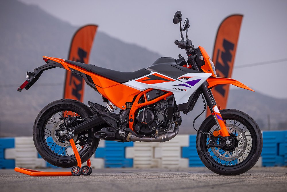 The 2025 KTM 390 staged at the Apex Motorsports park with KTM flags and a mountain in the background.