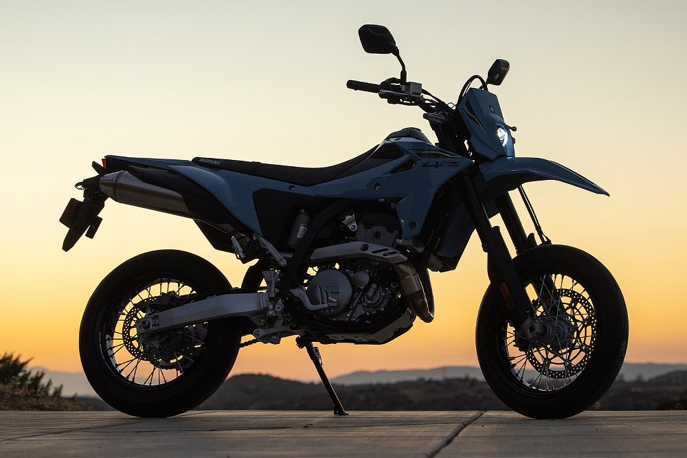 A silhouette DR-Z4SM stands with the sun setting in the background.