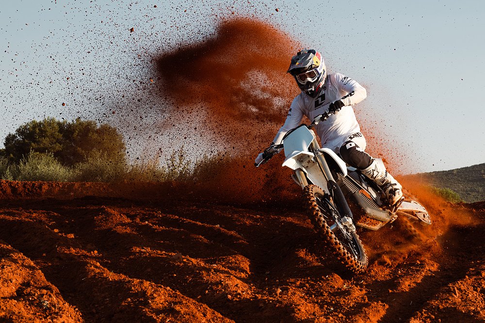 A Stark VARG MX 1.2 rider kicks up roost while riding on a motocross circuit.