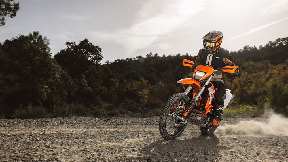 A dual-sport rider drives the 2026 KTM 390 Enduro R through a dirt trail.
